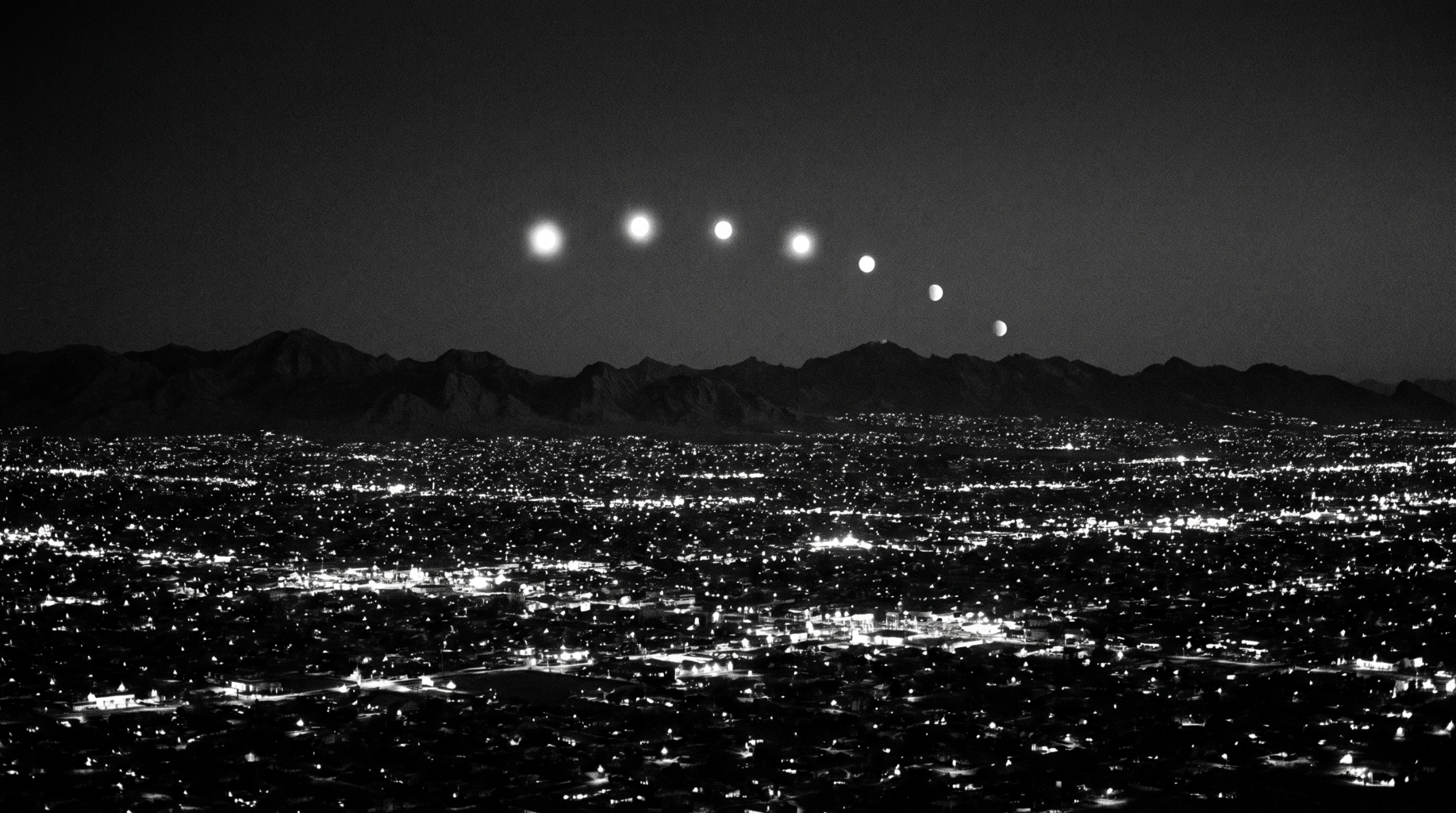 Artistic recreation of the Phoenix Lights: an arc of glowing orbs over the city skyline at night