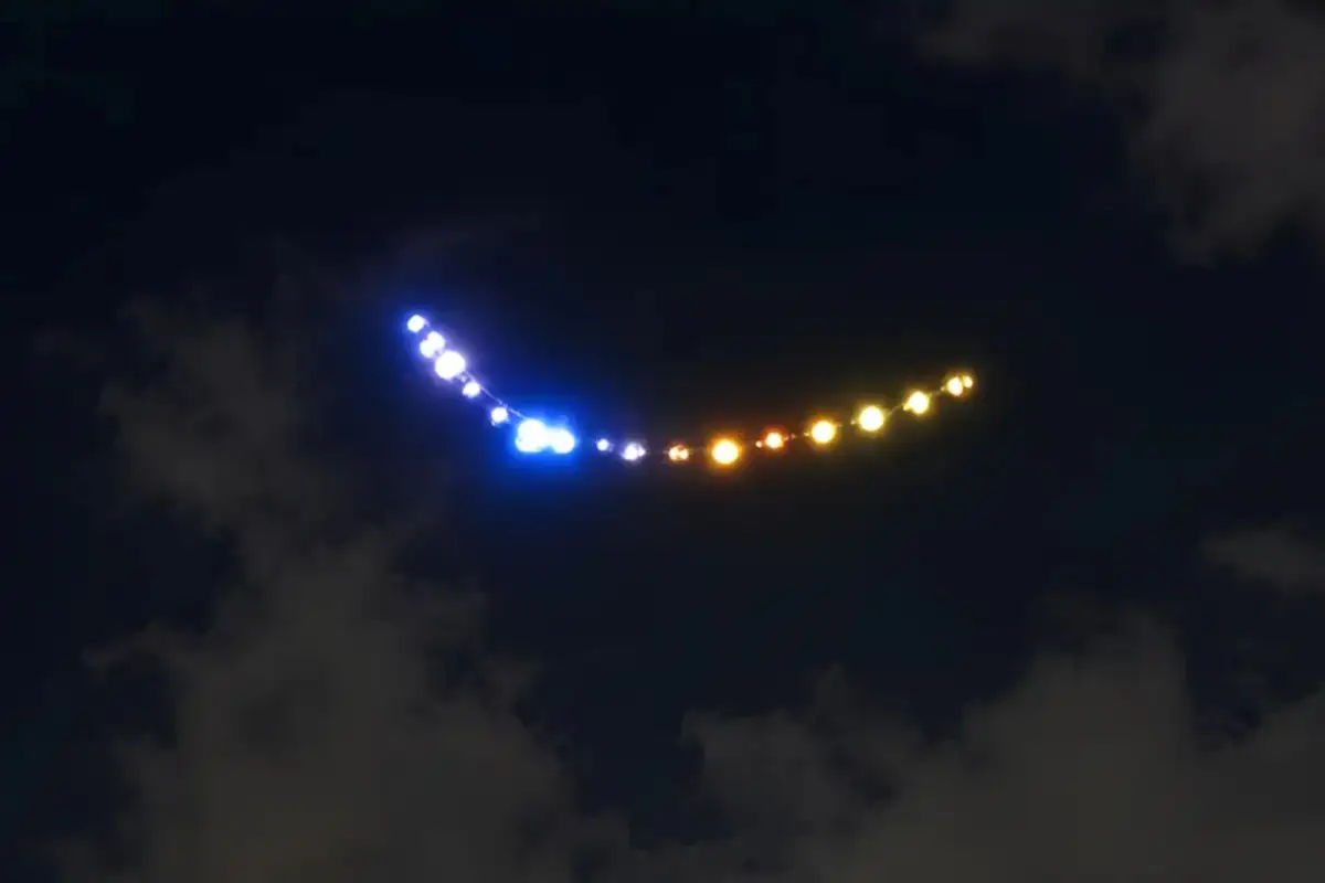 Strings of blue, white and amber lights in a curved line in the night sky, from the unidentified lights reported over Tehran in September 2026